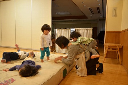 写真：保育士さんの背中によじ登っている様子