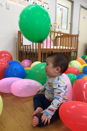 写真：たくさんの風船に囲まれてお座りしている子