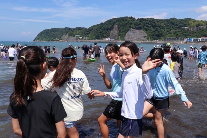 児童が海で遊んでいる写真