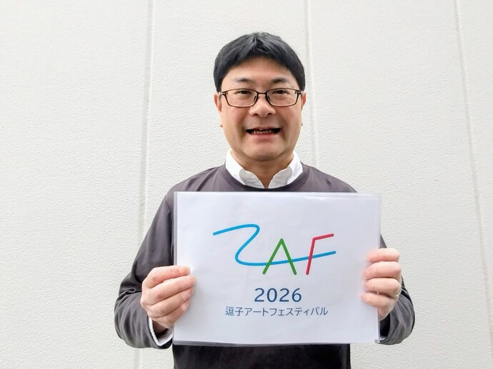 写真：新しいロゴが書かれた紙を持つ平戸さん