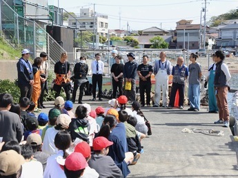 産卵床を沈めるために集まった関係者らが漁港で挨拶をしています