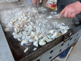 鉄板で調理されるアオリイカのバター焼きの写真です