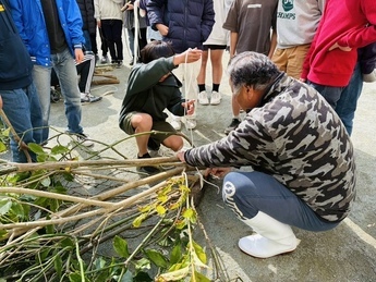 漁師と共に産卵床を作成する児童らの写真です。